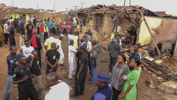 Eine Menschenmenge steht vor einem teilweise zerstörten Gebäude.