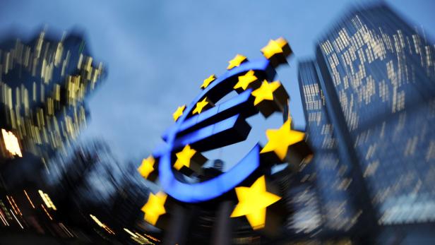 Das Euro-Symbol mit Sternen vor dem Hintergrund von Bürogebäuden.