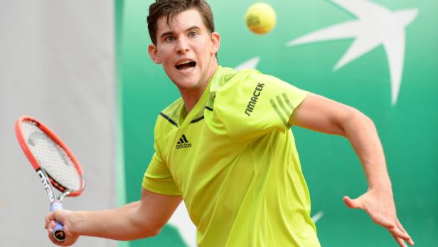 Dominic Thiem bei einem Tennisspiel mit gelbem Hemd und Tennisschläger.