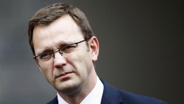 Ein Mann mit Brille und dunklem Anzug blickt in die Ferne.