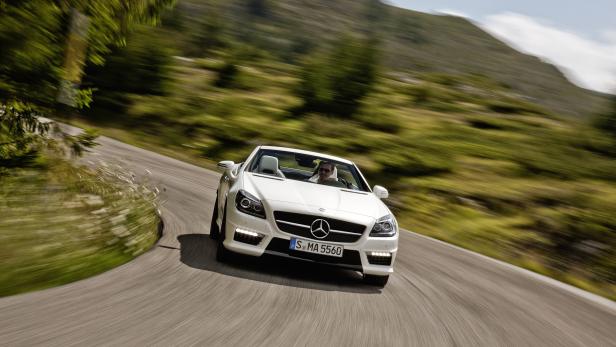 Ein weißer Mercedes-Benz SLK Roadster fährt auf einer kurvenreichen Straße.