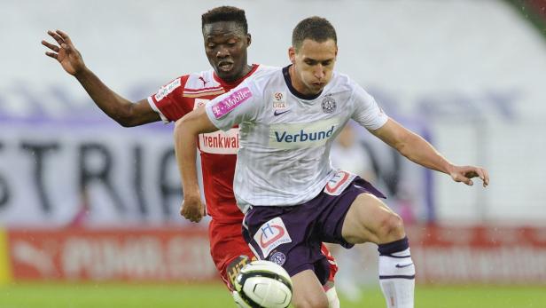 Zwei Fußballspieler kämpfen um den Ball während eines Spiels.