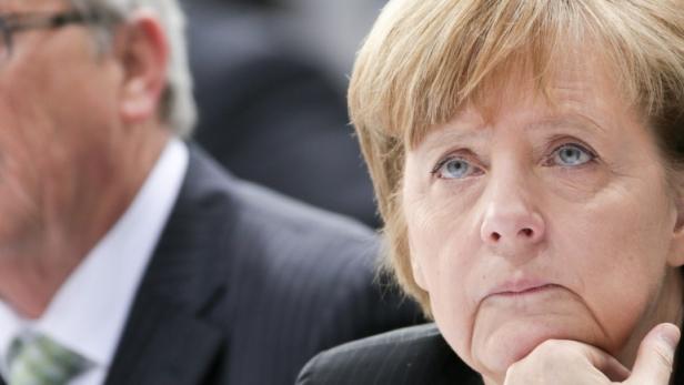 Angela Merkel mit nachdenklichem Gesichtsausdruck, neben ihr Jean-Claude Juncker.