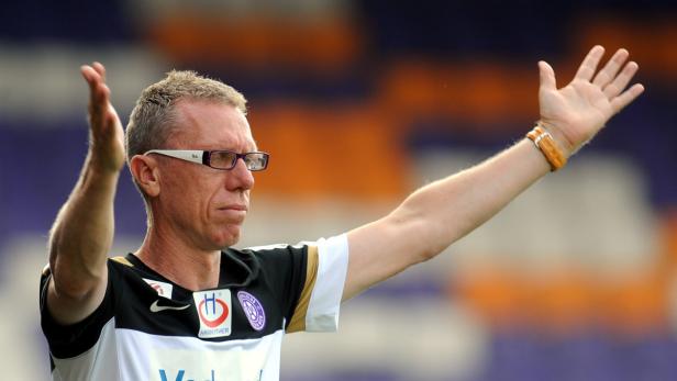 Ein Mann mit Brille gestikuliert mit erhobenen Händen.