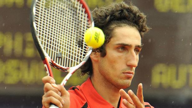 Ein Tennisspieler schlägt einen Ball mit seinem Schläger.