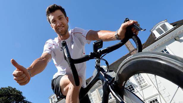 Ein Radfahrer gibt vor einem Gebäude mit seinem Daumen ein positives Zeichen.