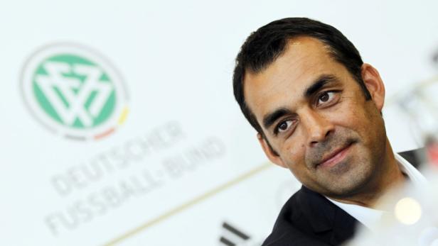 Ein Mann im Anzug vor dem Logo des Deutschen Fußball-Bundes.