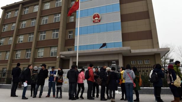 Eine Gruppe von Menschen steht vor einem Gebäude mit der chinesischen Flagge.
