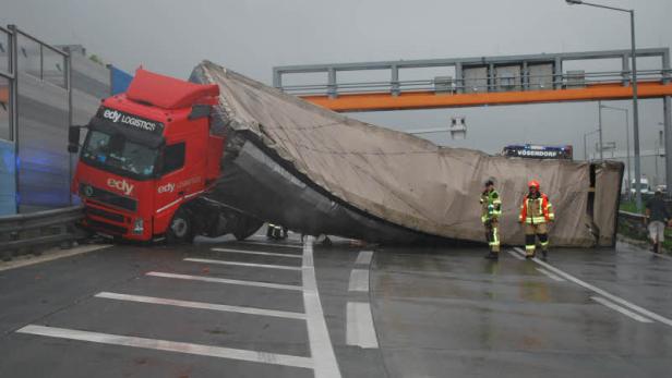 Ein umgestürzter LKW von Edy Logistics blockiert eine Autobahn bei regnerischem Wetter.