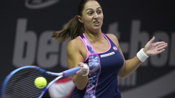 Eine Tennisspielerin schlägt einen Ball mit ihrem Schläger.