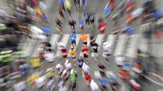 Eine Menschenmenge rennt bei einem Marathon über einen Zebrastreifen.