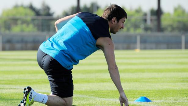 Ein Fußballspieler kniet auf dem Rasen und berührt den Boden.