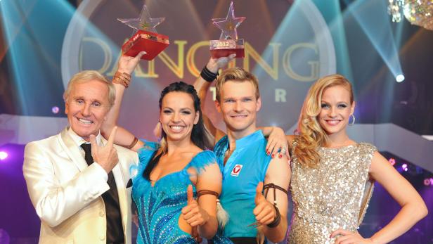 Die Gewinner der Show „Dancing Stars“ mit ihren Trophäen auf der Bühne.
