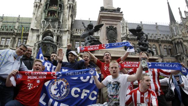 Fußballfans feiern mit Schals von Bayern München und Chelsea vor dem Marienplatz in München.