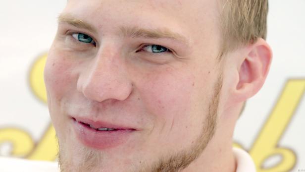Porträt eines jungen Mannes mit hellblonden Haaren und blauen Augen.