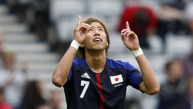 Ein japanischer Fußballspieler jubelt mit erhobenen Händen.
