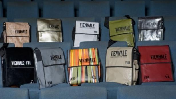 Eine Sammlung von Umhängetaschen der Viennale in verschiedenen Farben und Designs.