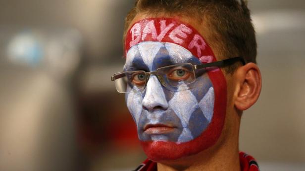 Ein Mann mit Gesichtsbemalung in den Farben des FC Bayern München.