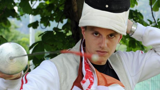 Ein junger Mann in Fechtausrüstung hält einen Degen.