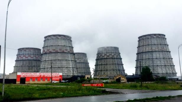 Mehrere Kühltürme eines Kraftwerks ragen in den bewölkten Himmel.