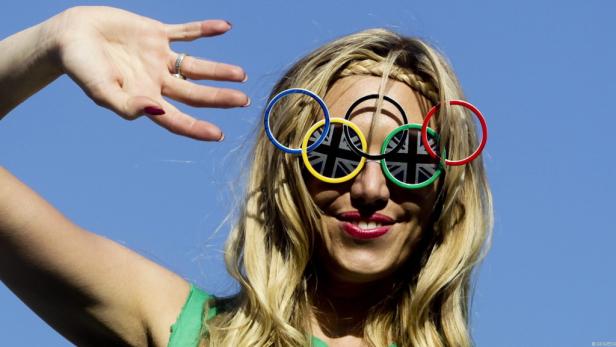 Eine Frau mit blonden Haaren trägt eine Sonnenbrille mit den olympischen Ringen und der britischen Flagge.