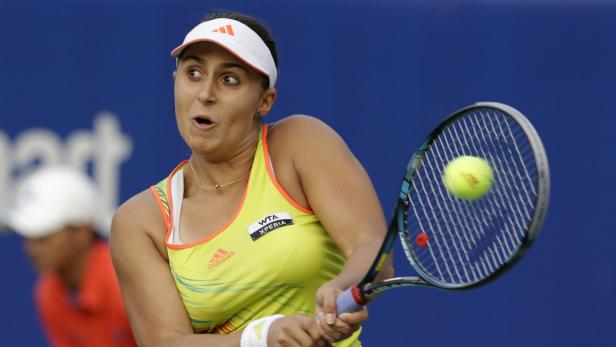 Eine Tennisspielerin schlägt einen Ball mit ihrem Schläger.