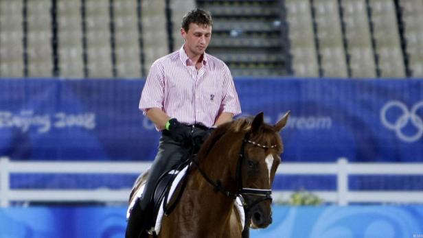 Ein Reiter auf einem braunen Pferd vor dem Hintergrund der Olympischen Spiele 2008 in Peking.