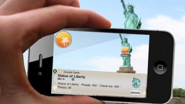 Eine Person fotografiert die Freiheitsstatue mit einem Smartphone.