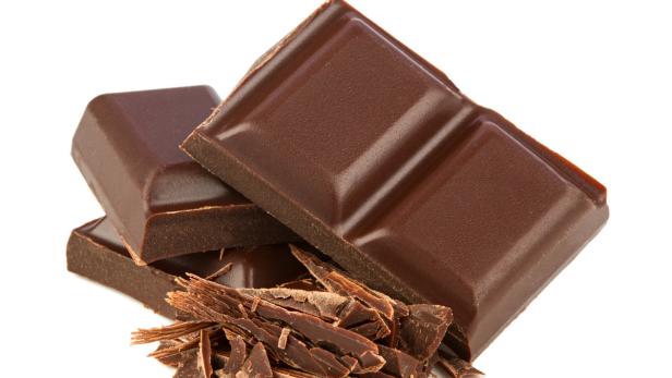 Drei Stücke dunkler Schokolade mit Schokoladenspänen.