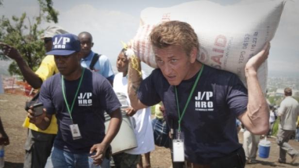 Sean Penn trägt einen Sack Hilfsgüter über die Schulter.