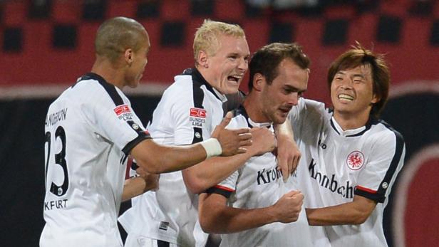 Mehrere Fußballspieler von Eintracht Frankfurt feiern gemeinsam auf dem Spielfeld.