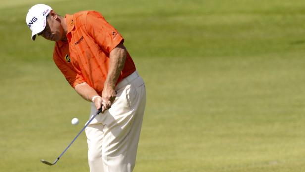 Ein Golfspieler schlägt einen Ball auf einem grünen Golfplatz.