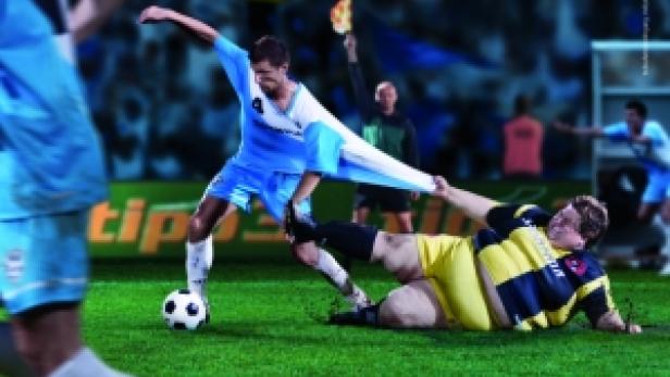 Ein Fußballspieler wird von einem übergewichtigen Mann auf dem Spielfeld am Trikot gezogen.