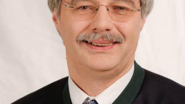 Porträt eines Mannes mit Brille, Schnurrbart und Trachtenjacke.
