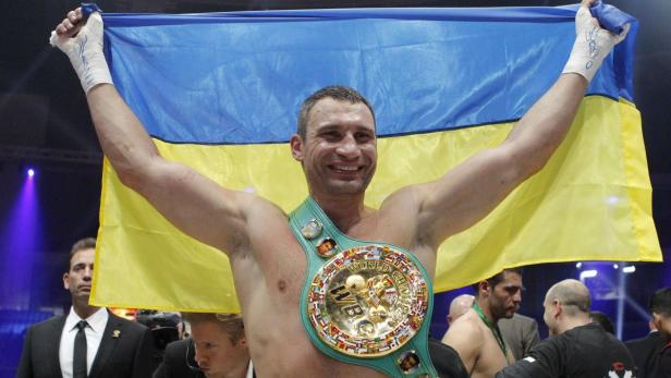Vitali Klitschko mit dem ukrainischen Flagge und einem Weltmeistergürtel.