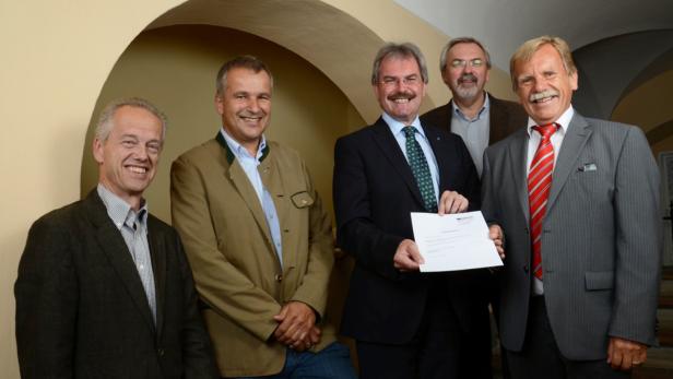 Fünf Männer posieren für ein Gruppenfoto in einem Gebäude.