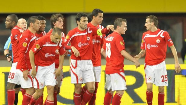 Eine Gruppe von Fußballspielern in roten Trikots steht auf dem Spielfeld.
