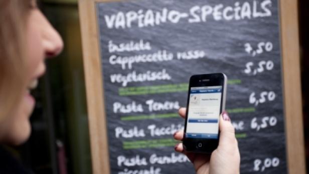 Eine Frau fotografiert die Speisekarte von Vapiano mit ihrem Smartphone.
