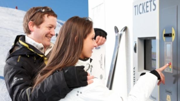 Ein Paar kauft am Automaten Skipässe für den Skiurlaub.