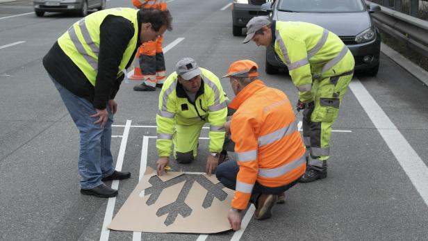 Arbeiter der Asfinag bringen eine neue Bodenmarkierung, die ihre Farbe nach Temperatur wechselt, an einer Stelle auf der Südautobahn (A2) in der Steiermark auf der Fahrbahn an.