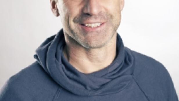 Ein Mann mit grau meliertem Haar lächelt in die Kamera.