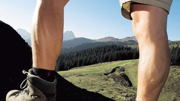 Ein Wanderer steht mit Bergschuhen in den Bergen.