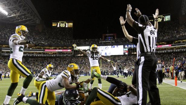 Ein Footballspieler der Green Bay Packers feiert einen Touchdown vor einem Schiedsrichter.