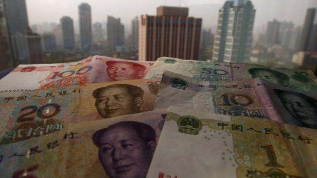 Verschiedene chinesische Yuan-Banknoten liegen vor einer Skyline.