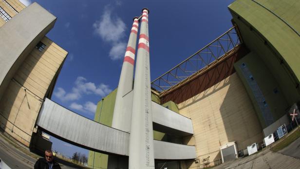 Zwei hohe Schornsteine mit rot-weißen Streifen ragen vor einem Industriegebäude in den Himmel.
