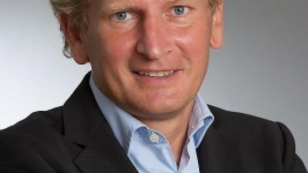 Ein Mann mit blonden Haaren und blauem Hemd lächelt in die Kamera.