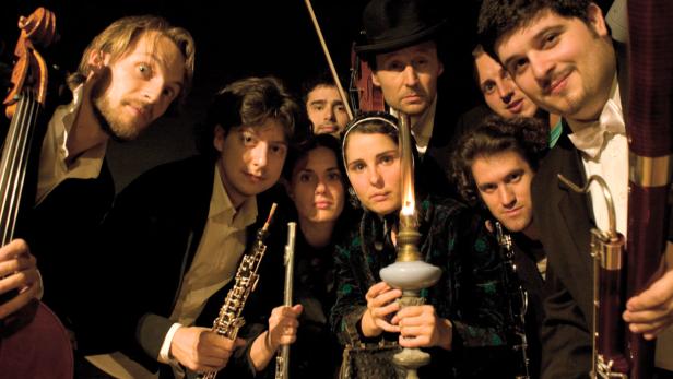 Ein Ensemble von Musikern mit verschiedenen Instrumenten posiert für ein Gruppenfoto.