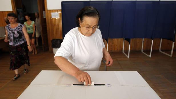 Eine Frau wirft einen Stimmzettel in eine Wahlurne.