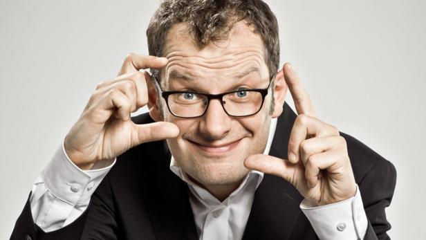 Ein Mann mit Brille formt mit seinen Händen einen Rahmen um sein Gesicht.