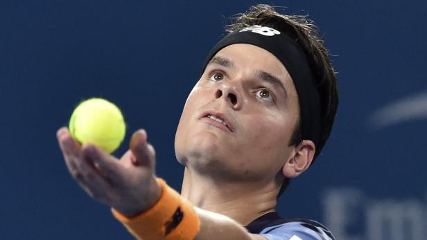 Ein Tennisspieler mit Stirnband wirft einen Tennisball hoch.